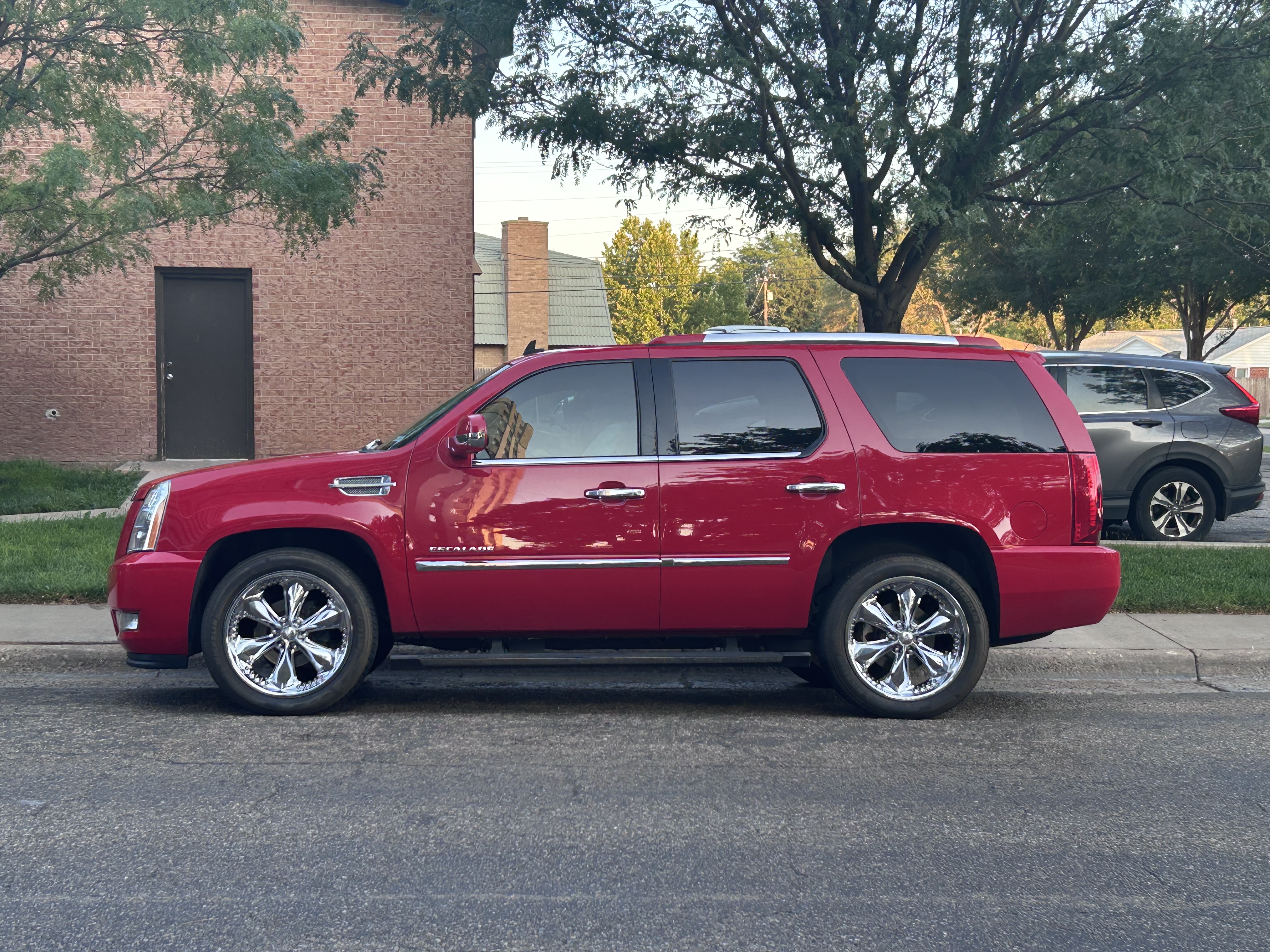 Red Cadillac Escalade parked beside a brick building